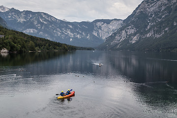 Image showing People rowing in the canoe on tranquil overcast morning at lake Bohinj, Alps mountains, Slovenia.