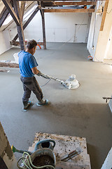 Image showing Laborer polishing sand and cement screed floor.