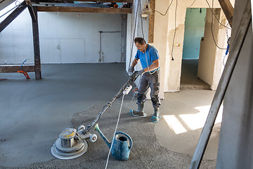 Image showing Laborer polishing sand and cement screed floor.