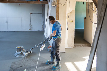 Image showing Laborer polishing sand and cement screed floor.