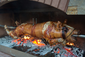 Image showing Piglet on a spit over a wood fire.