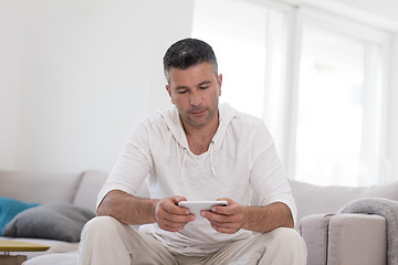 Image showing young man using a mobile phone  at home