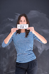 Image showing woman holding a banknote in front of chalk drawing board