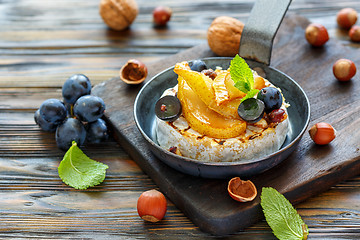 Image showing Baked camembert with pears, black grapes and hazelnuts.