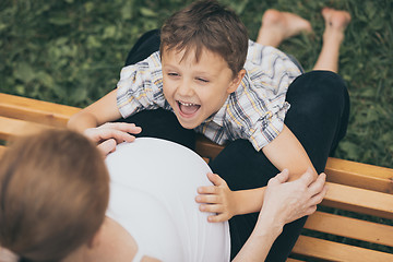 Image showing Happy little boy hugging mother in the park at the day time.