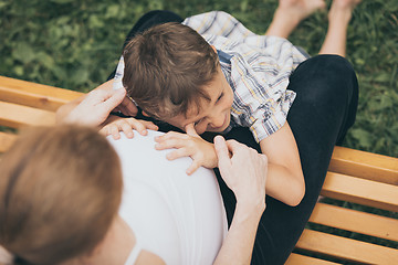 Image showing Happy little boy hugging mother in the park at the day time.