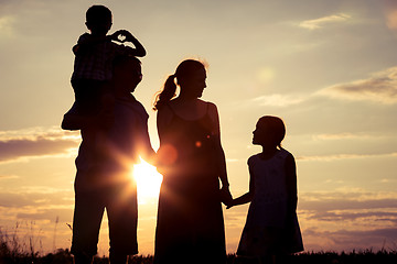 Image showing Happy family standing on the field at the sunset time.