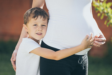 Image showing Happy little boy huging mother in the park at the day time.