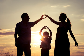 Image showing Happy family standing in the park at the sunset time.