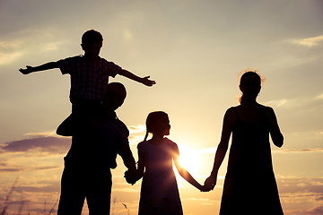 Image showing Happy family standing on the field at the sunset time.