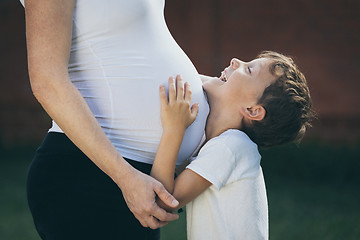 Image showing Happy little boy huging mother in the park at the day time.