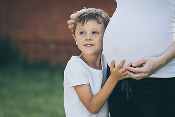 Image showing Happy little boy huging mother in the park at the day time.