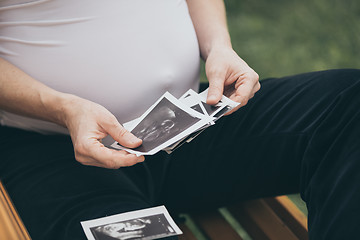 Image showing pregnant woman sitting on the bench and loocking ultrasound scan