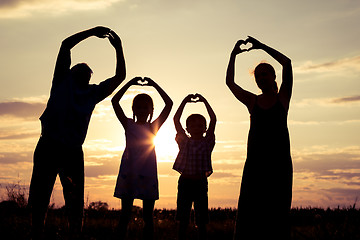 Image showing Happy family standing on the field at the sunset time.