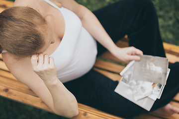 Image showing pregnant woman sitting on the bench and loocking ?hildren\'s pho