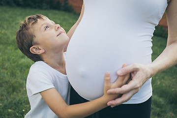 Image showing Happy little boy huging mother in the park at the day time.