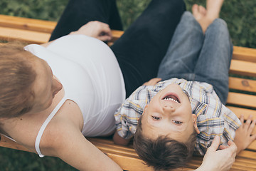 Image showing Happy little boy hugging mother in the park at the day time.