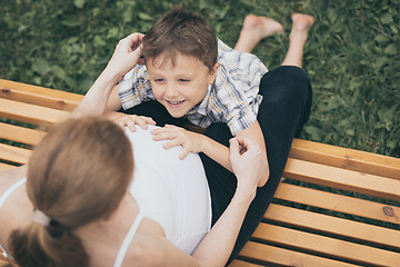 Image showing Happy little boy hugging mother in the park at the day time.