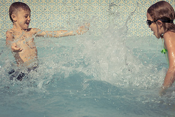 Image showing Two happy children playing on the swimming pool at the day time.