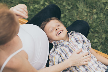 Image showing Happy little boy hugging mother in the park at the day time.