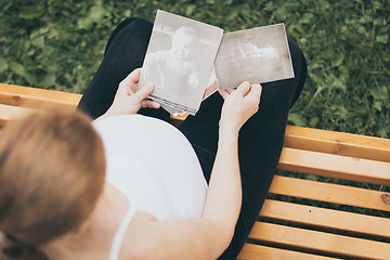 Image showing pregnant woman sitting on the bench and loocking ?hildren\'s pho