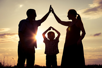 Image showing Happy family standing on the field at the sunset time.