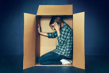 Image showing Introvert concept. Woman sitting inside box and working with phone