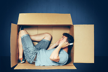 Image showing Introvert concept. The man sitting inside box and working with laptop