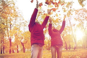 Image showing happy young couple throwing autumn leaves in park