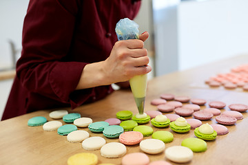 Image showing chef with injector squeezing filling to macarons