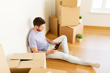 Image showing man with tablet pc and boxes moving to new home