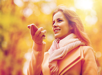 Image showing woman recording voice on smartphone in autumn park