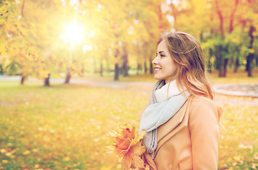 Image showing beautiful woman with maple leaves in autumn park