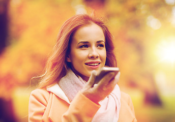 Image showing woman recording voice on smartphone in autumn park