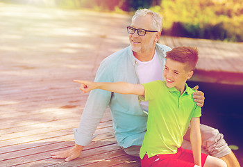 Image showing grandfather and grandson sitting on river berth