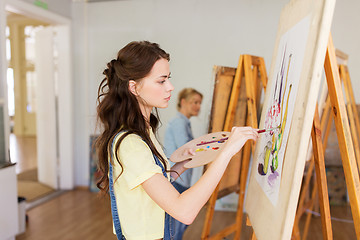 Image showing student girl with easel painting at art school