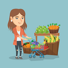 Image showing Young caucasian woman pushing a supermarket cart.