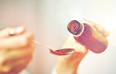 Image showing woman pouring medication from bottle to spoon