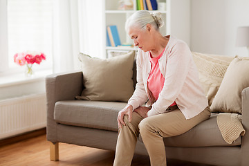 Image showing senior woman suffering from pain in leg at home