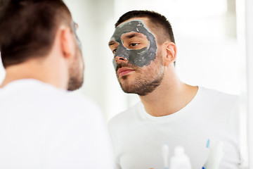 Image showing young man with clay mask on face at bathroom