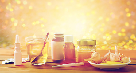 Image showing drugs, thermometer, honey and cup of tea on wood