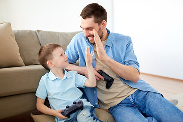 Image showing father and son with gamepads doing high five