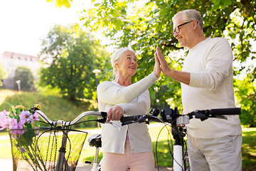 Image showing senior couple with bikes making high five at park