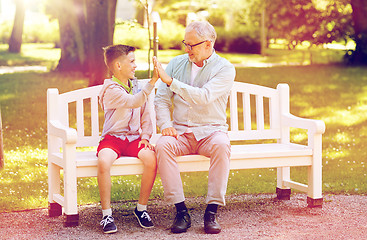 Image showing old man and boy making high five at summer park