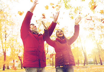 Image showing happy young couple throwing autumn leaves in park