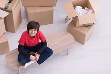 Image showing boy sitting on the table with cardboard boxes around him top vie