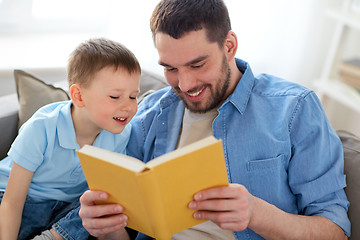 Image showing happy father and son reading book sofa at home