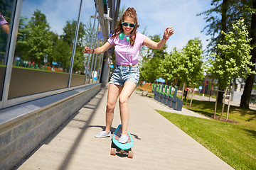 Image showing happy teenage girl in shades riding on longboard