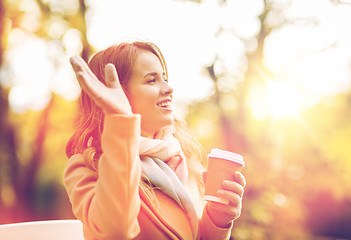 Image showing happy young woman drinking coffee in autumn park