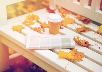 Image showing newspaper and coffee cup on bench in autumn park